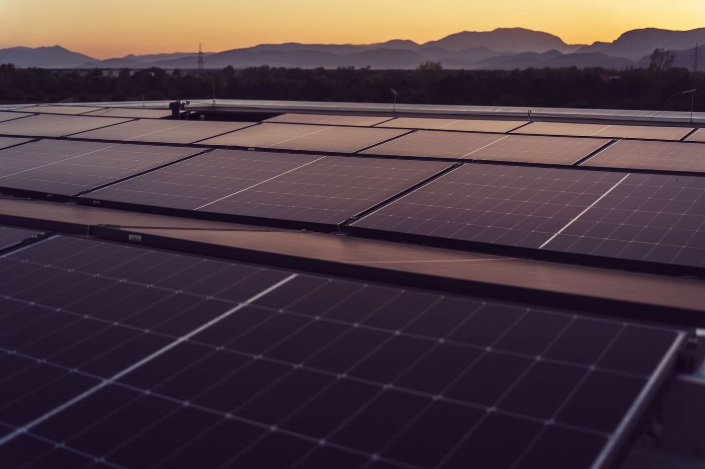 Rooftop solar panels at sunset with mountains in the distance